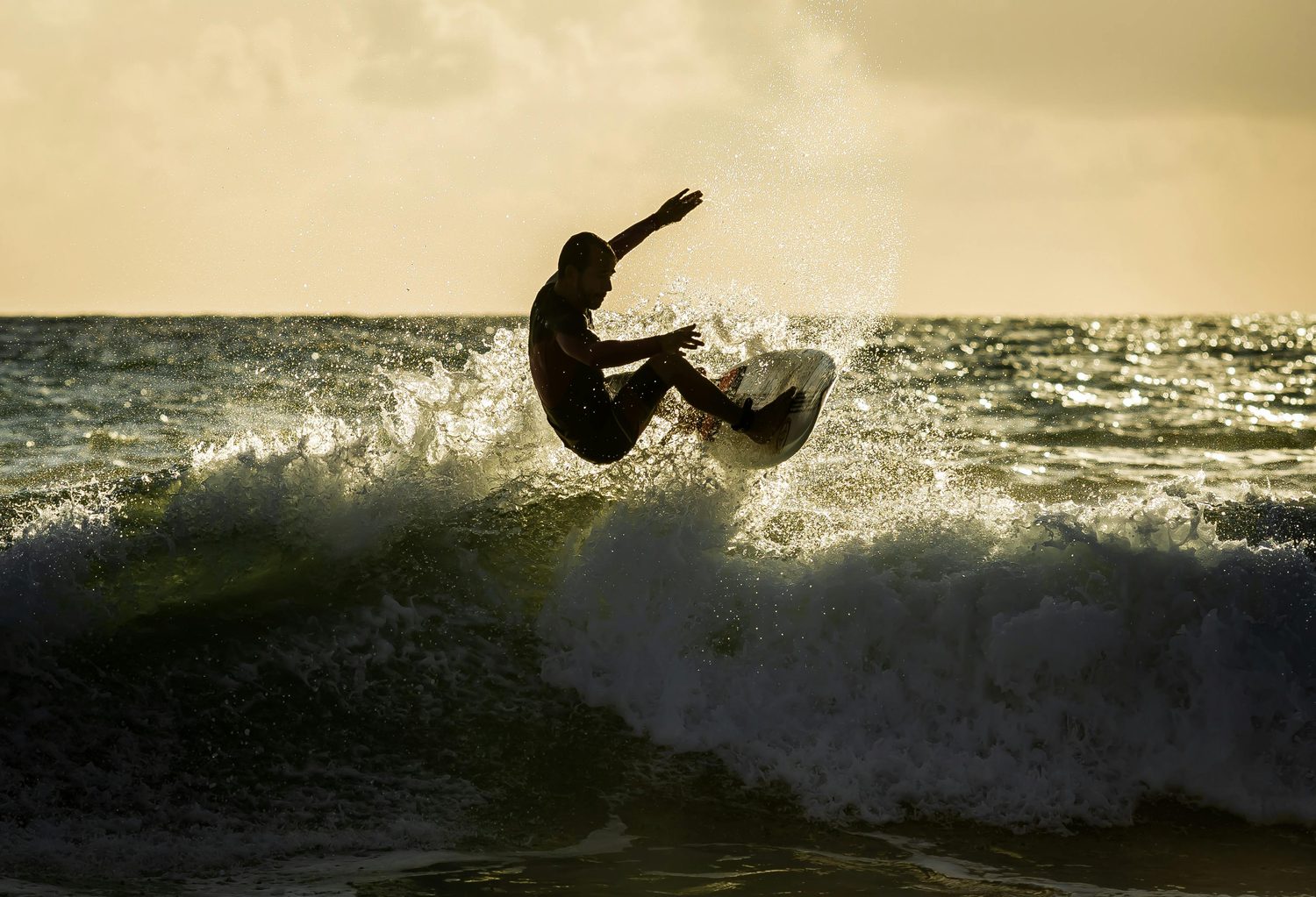 Surfista recortando una ola al atardecer