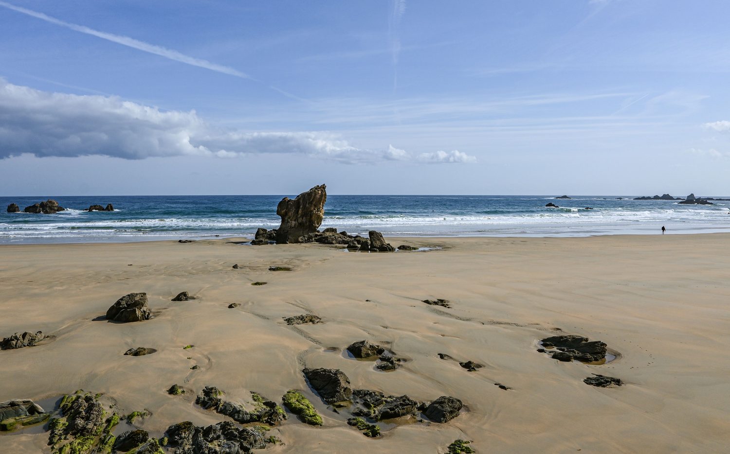 Playa de arena dorada con rocas en marea baja